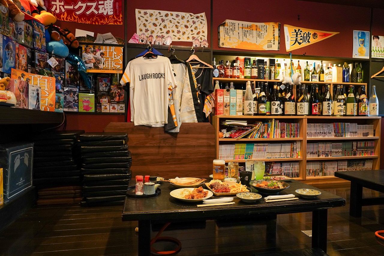 座敷席に並んだ料理とドリンク、漫画が並ぶ本棚