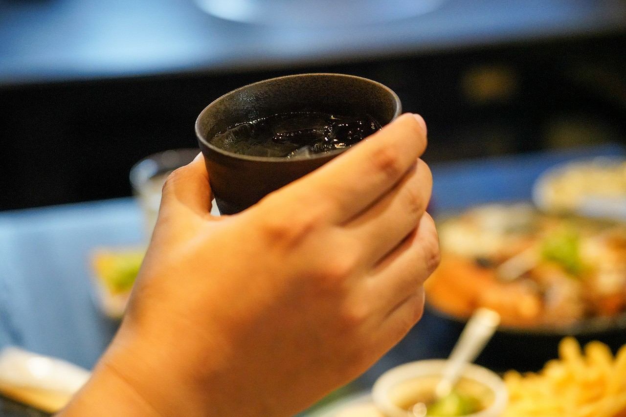 ドリンクを手に取る客と料理